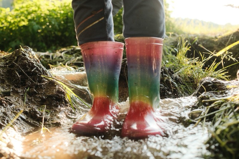 Bunte Gummistiefel im Matsch, von der tiefen Sonne beleuchtet