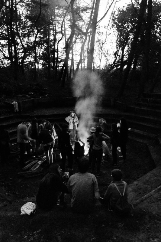Menschen sitzen im Kreis um ein Lagerfeuer